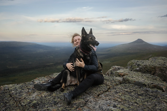 en kvinna kramar om en hund uppe på en fjälltopp